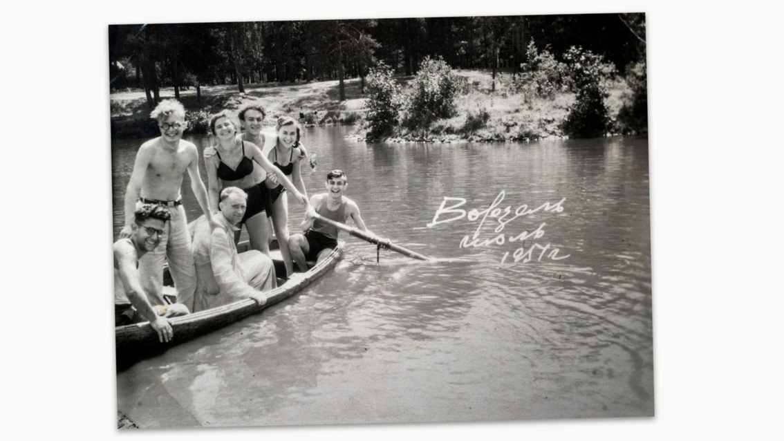 Schwarzweißfoto: Unbeschwerte junge Leute in einem kleinen Ruderboot lachen in die Kamera.