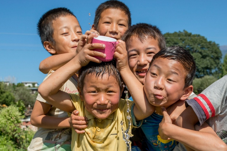 Fünf kleine Jungs, eng gedrängt, albern mit einer wassergefüllten Taser herum und lachen in die Kamera.