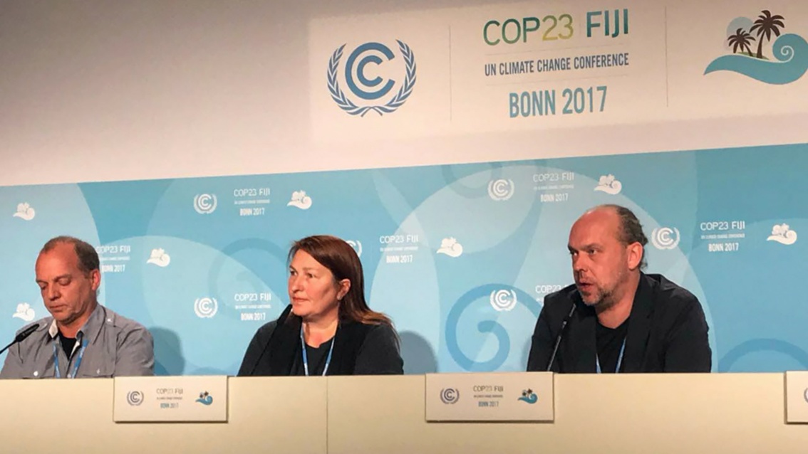 Eine Frau zwischen zwei Männern. Sie sitzen auf einem Podium, hinter ihnen der Schriftzug «COP23 Fiji, UN Climate Change Conference, Bonn 2017».