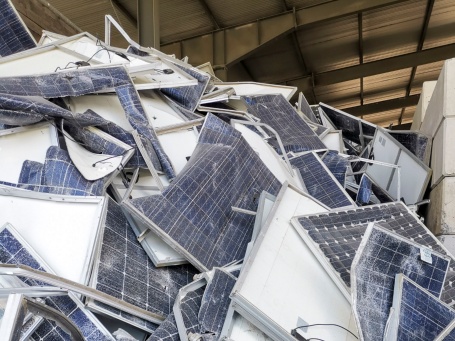 In einer Lagerhalle stapeln sich alte kaputte Solarmodule zu einem großen Haufen.