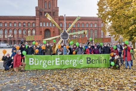 Vor dem Berliner Roten Rathaus sind etwa 40 Menschen zu einem Gruppenbild aufgestellt und halten einen Papp-Fernsehturm mit goldenen Strahlen.