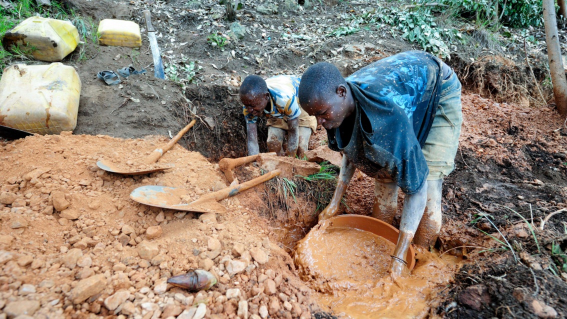 Bergbau mit einfachsten Mitteln: Zwei Männer waschen rote schlammige Erde in Schüsseln.