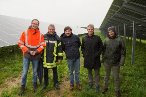 Fünf Männer stehen nebeneinander zwischen Photovoltaikmodulen