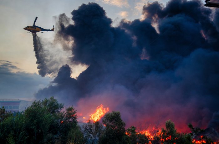 Löschhubschrauber schwebt über Waldbrand und wirft Wasser ab