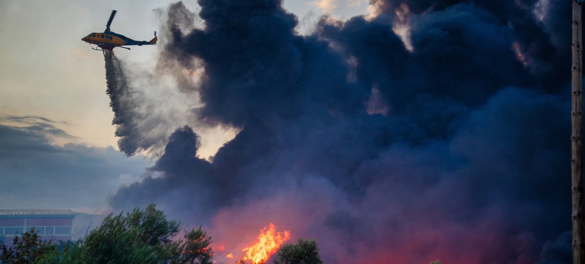 Löschhubschrauber schwebt über Waldbrand und wirft Wasser ab