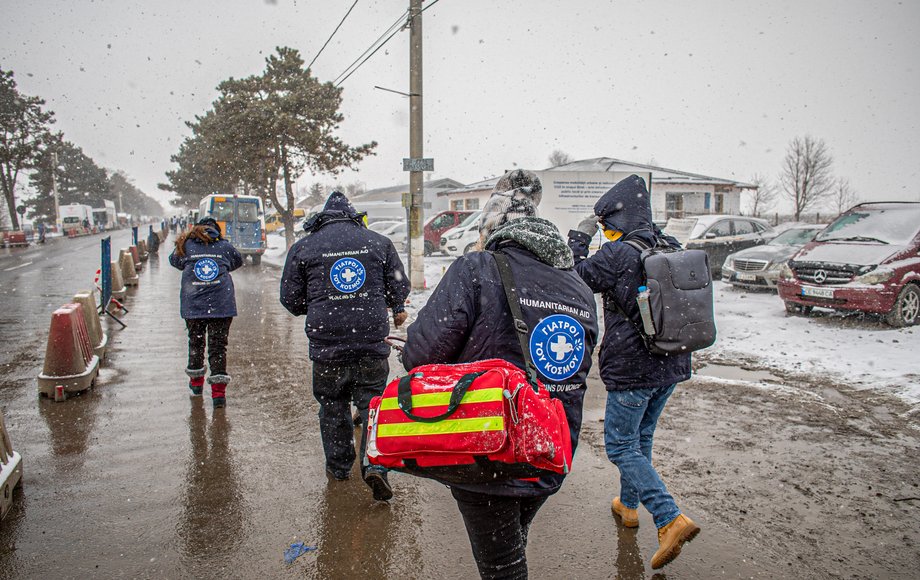 Vier Menschen von Ärzte der Welt von hinten gesehen auf einer Straße im Schneeregen