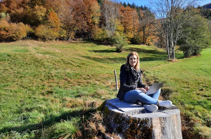 Rebecca Diewald sitzt auf einem Baumstumpf.