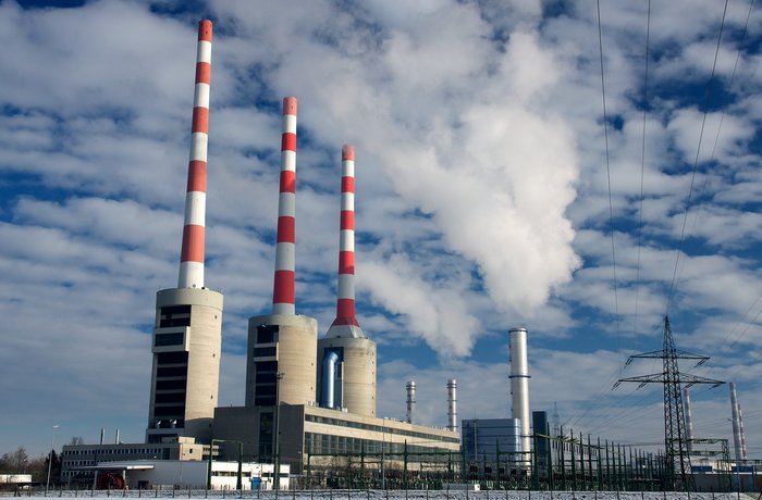 Gaskraftwerk mit mehreren Schornsteinen unter bewölktem Himmel.