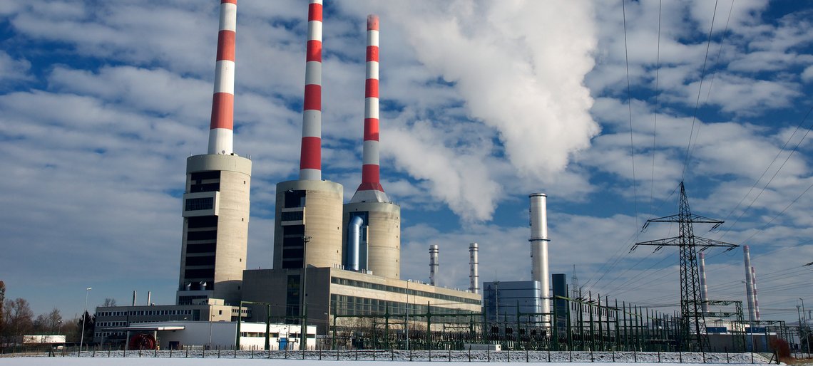 Gaskraftwerk mit mehreren Schornsteinen unter bewölktem Himmel.