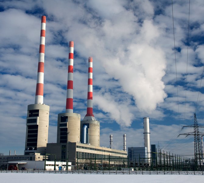 Gaskraftwerk mit mehreren Schornsteinen unter bewölktem Himmel.