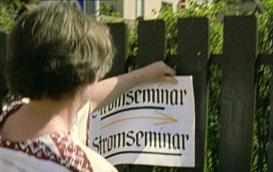 Frau hängt ein Plakat mit der Aufschrift Stromseminar auf