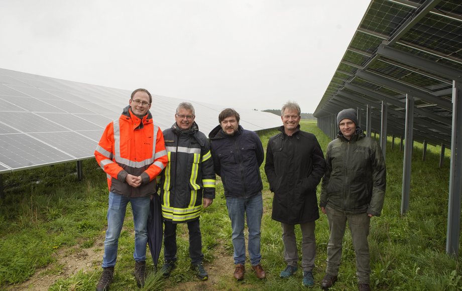 Fünf Menschen nebeneinander zwischen Solarmodulen