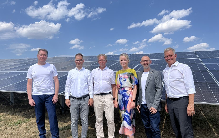 Sechs Menschen stehen nebeneinander auf einem Feld vor Solarpanels im Solarpark Trichtingen.