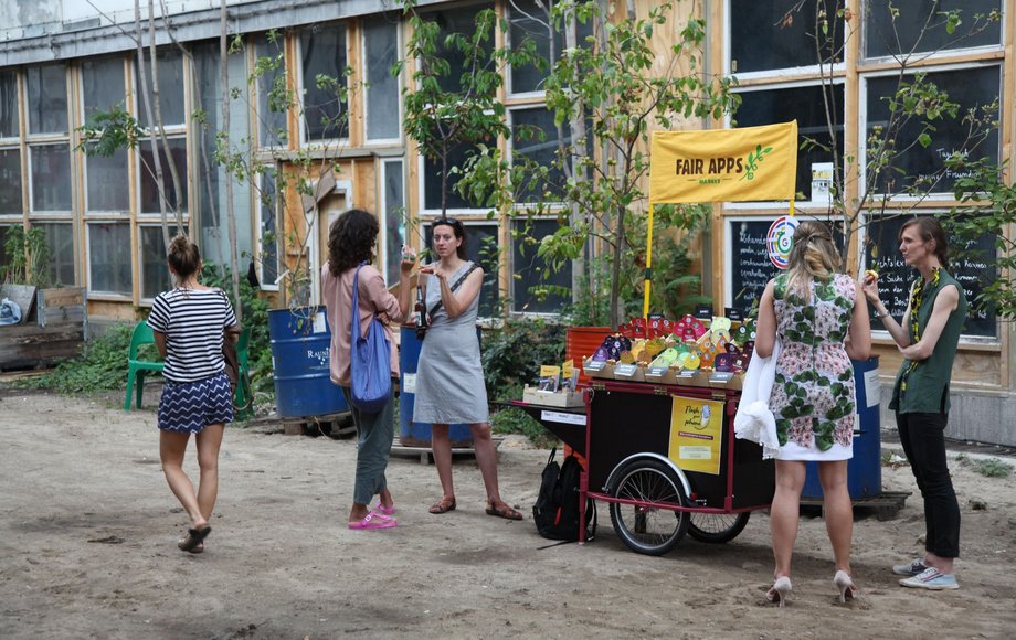 Mobiler Infostand „Fair Apps Market" von Topio im Freien, Besucherinnen im Gespräch mit Standbetreuerinnen.