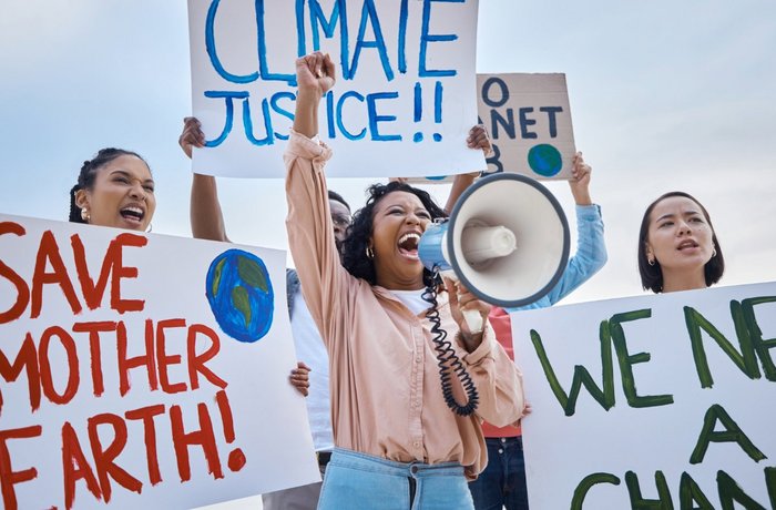 Drei junge Frauen protestieren für Klimagerechtigkeit