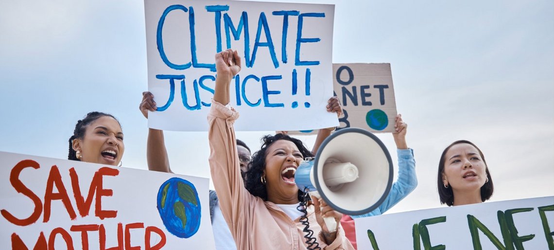 Drei junge Frauen protestieren für Klimagerechtigkeit