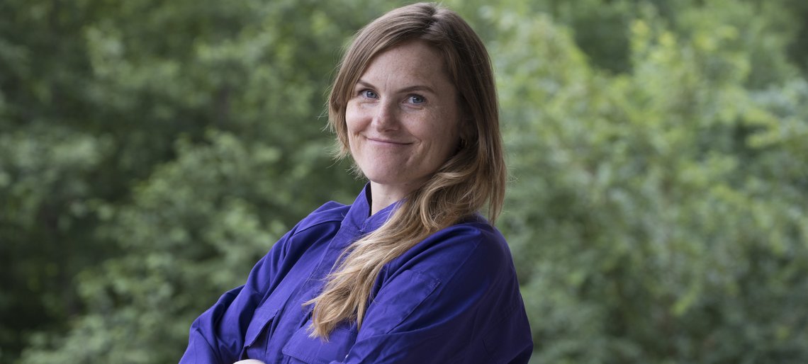 Cesy Leonard im Overall vor Büschen