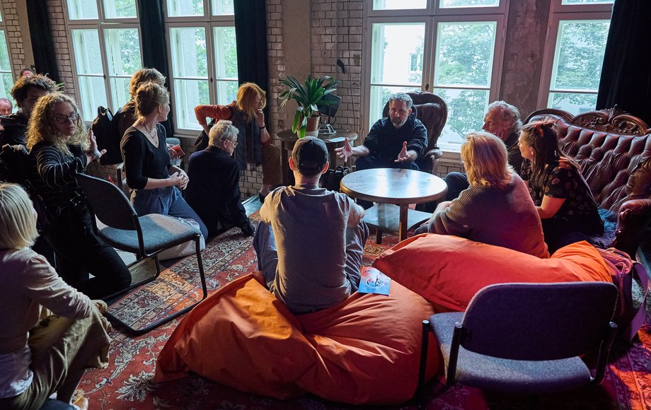Eine Gruppe sitzt im Kreis auf Stühlen und Sitzhockern.