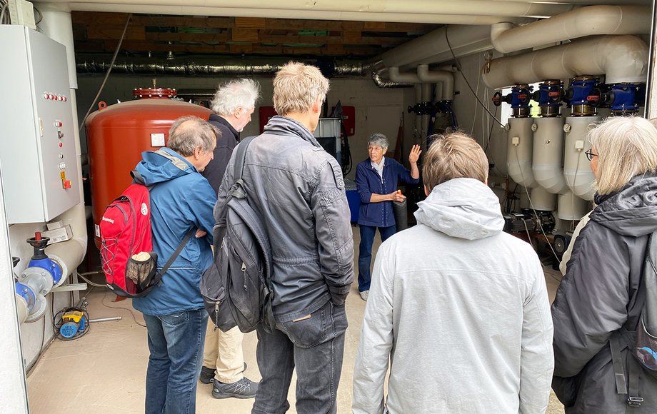 Gruppe steht um eine Frau herum, im Hintergrund eine Garage