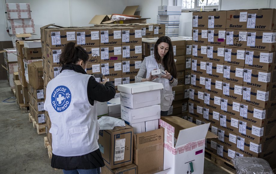 Zwei Frauen in einem Lager mit vielen Kartons packen Pakete mit Medikamenten