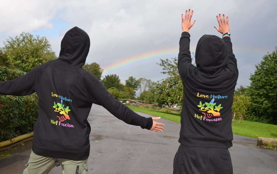 Zwei Leute mit Hoodie vor Regenbogen