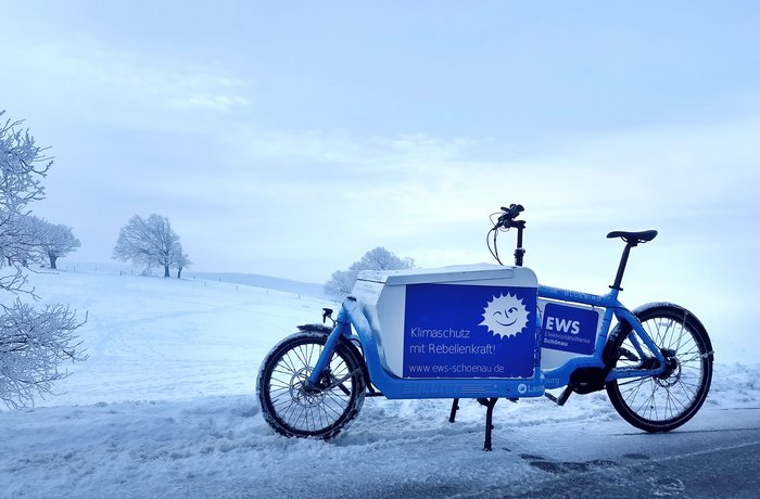 Ein Lastenrad im EWS-Design steht inmitten einer Schneelandschaft