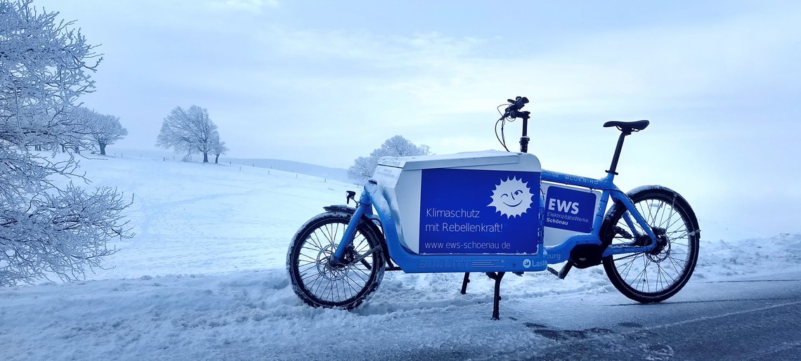 Ein Lastenrad im EWS-Design steht inmitten einer Schneelandschaft