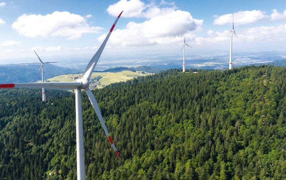 Luftaufnahme von fünf Windkraftanlagen im Wald