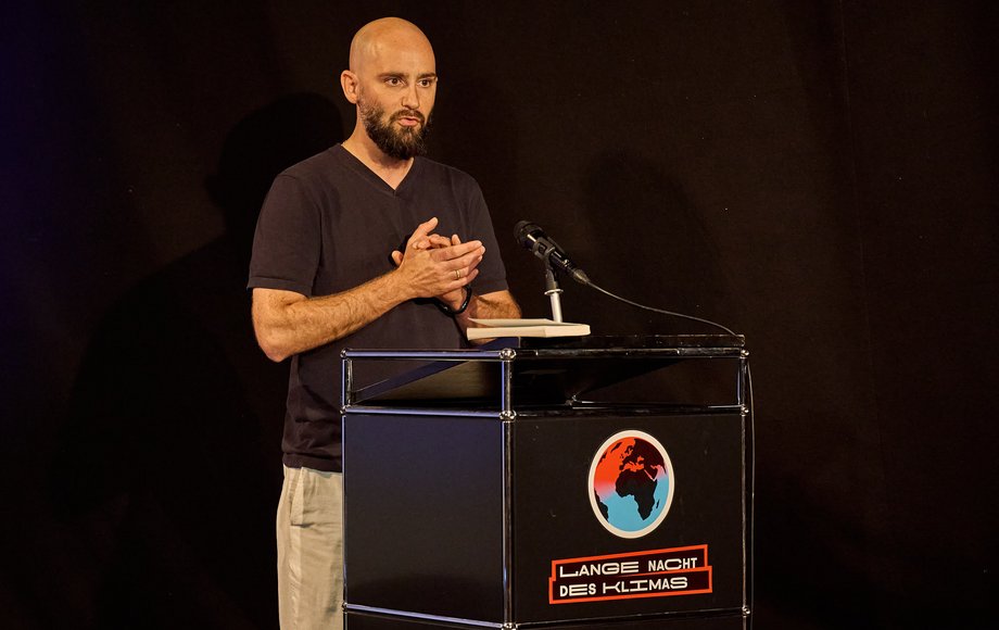 Mann am Rednerpult vor dunklem Hintergrund