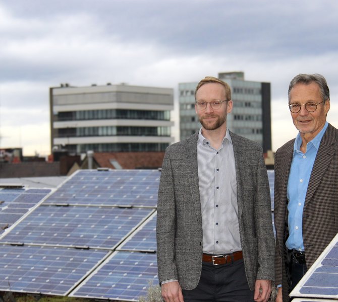 Bertram und Johannes Späth neben Solarmodulen auf einem Dach
