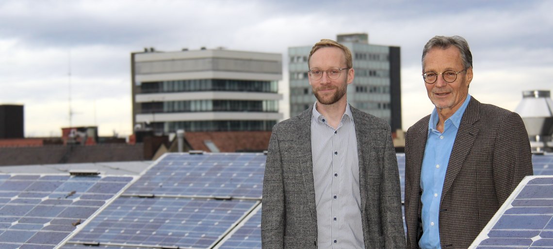 Bertram und Johannes Späth neben Solarmodulen auf einem Dach