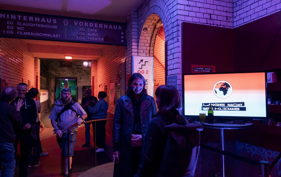 Eingangsbereich der Kulturfabrik in der Nacht, bunt beleuchtet, mit zahlreichen Menschen.