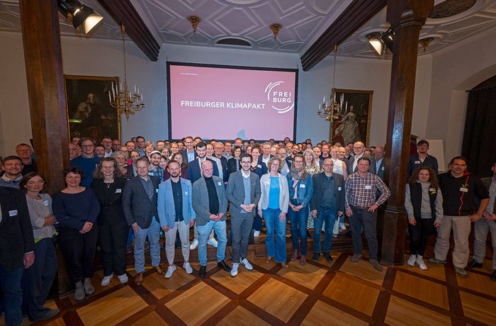 Zu sehen ist eine Gruppe von Mitgliedern des Freiburger Klimapaktes in einem Saal im Historischen Kaufhaus in Freiburg.