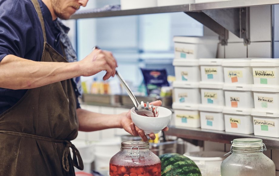 Koch gibt eine Kelle eingelegter Früchte in eine Schüssel