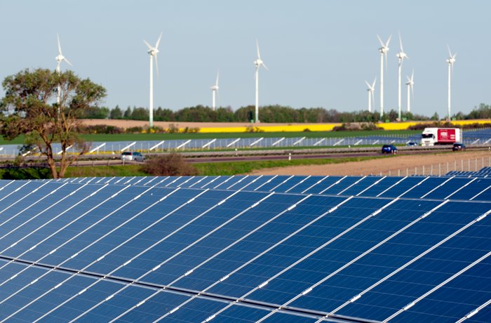 Windkrafträder und Solarmodule in einem Rapsfeld