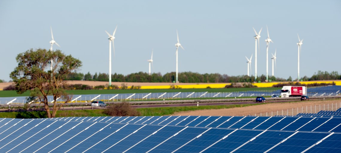 Windkrafträder und Solarmodule in einem Rapsfeld
