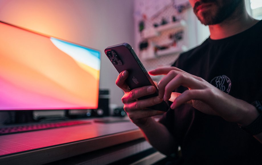 Mann mit Smartphone sitzt am Schreibtisch