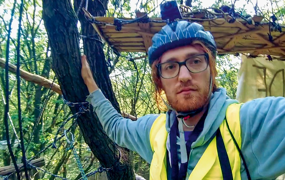 Mann mit Fahrradhelm macht ein Selfie, im Hintergrund Baumwipfel