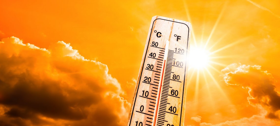 Leuchtende Sonne am orangen Himmel mit Thermometer als Symbol für Hitzewelle