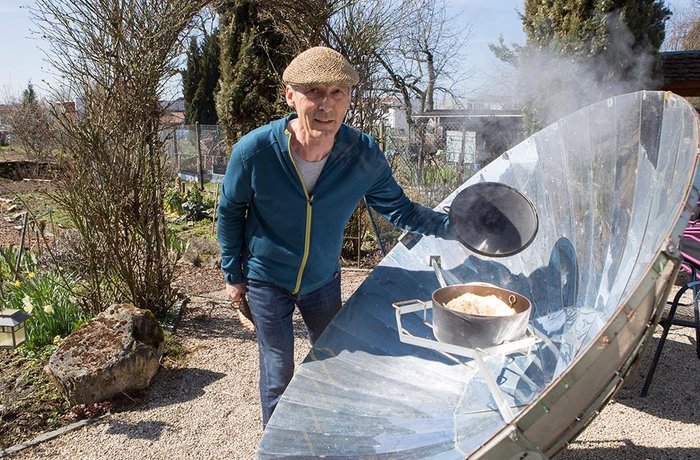 Der Solarbäcker hebt den Deckel seines Ofens – Dampf steigt auf.