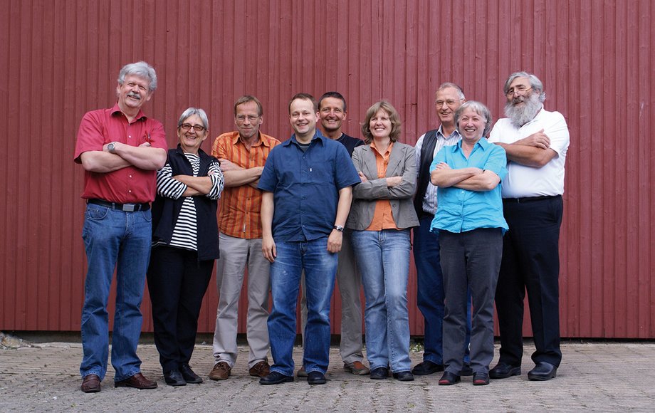 Gruppenbild von zehn Menschen vor roter Scheunenwand