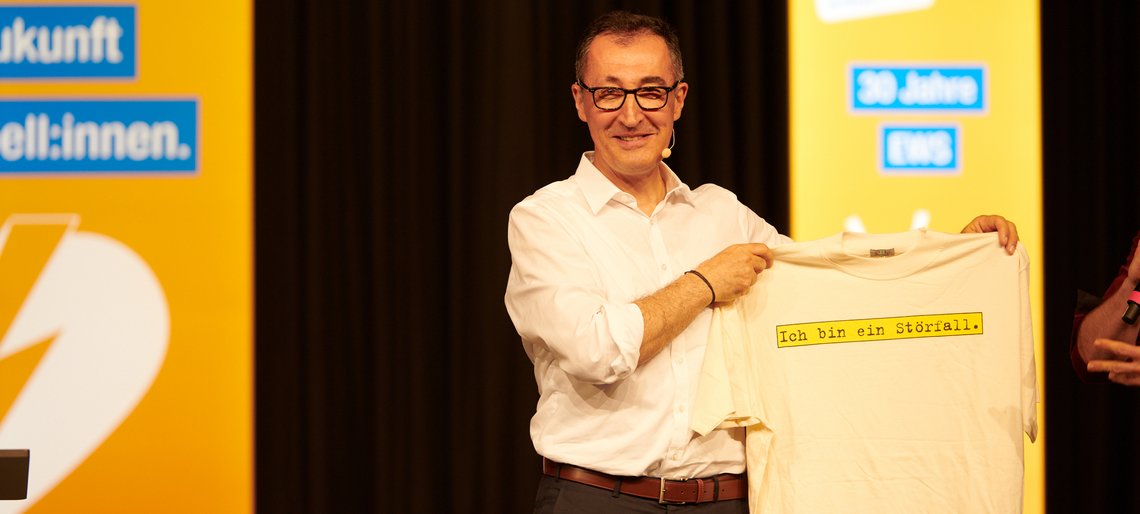 Cem Özdemir hält ein T-Shirt mit der Aufschrift "Ich bin ein Störfall" hoch