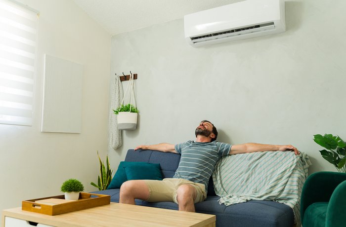 Mann hängt auf dem Sofa und genießt die Luft aus der Klimaanlage