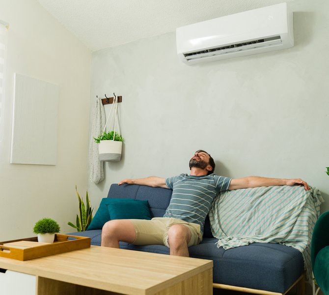 Mann hängt auf dem Sofa und genießt die Luft aus der Klimaanlage