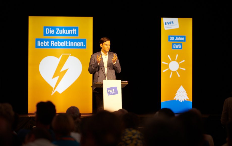 Frontansicht von Andreas Wieg auf der Bühgne zwischen zwei beleuchteten Paneelen