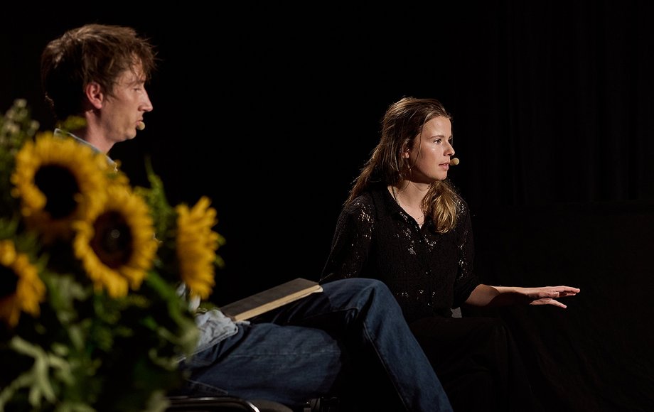 Nikolaj Schultz und Luisa Neubauer sitzen auf einer dunklen Theaterbühne