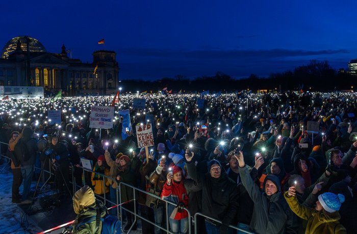 Große Menschenmenge vor Berliner Reichstag, die bei Nacht Taschenlampen leuchten lasen