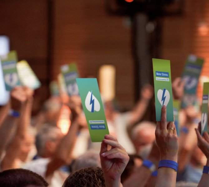 Menschen halten auf einer Versammlung Stimmkarten in die Höhe