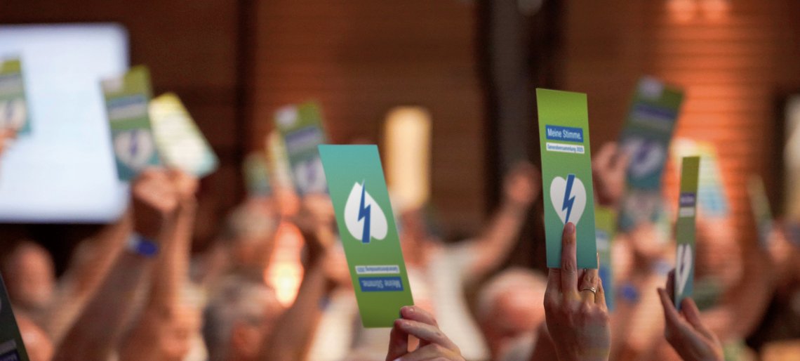 Menschen halten auf einer Versammlung Stimmkarten in die Höhe