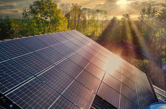 Solarpaneele und Sonnenreflexionen auf dem Dach vor blauem Himmel.